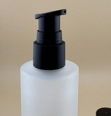 Botella de vidrio transparente mate con bomba de tratamiento negra para cosméticos